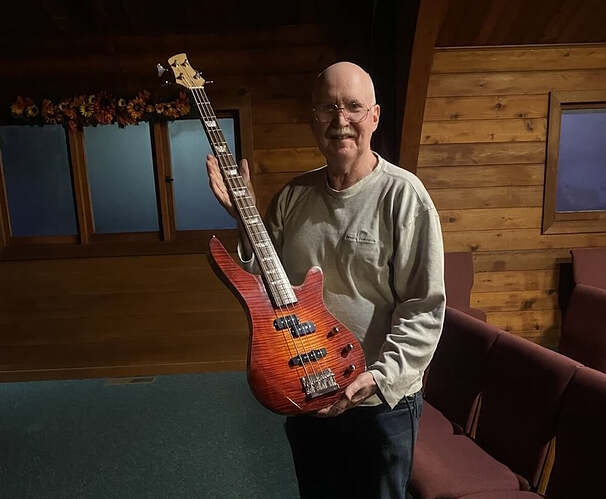 Bill Adam holding the finished bass, showing the lava burst flamed maple top